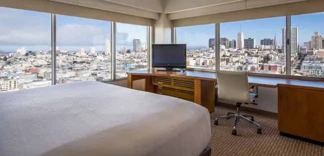 our corner king room showing king size bed and wrap-around windows for a view of Nob Hill on two sides