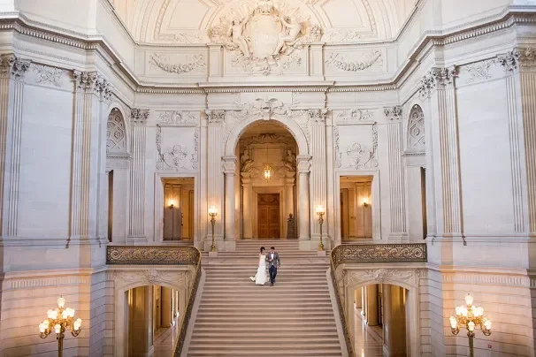 image of a bride and groom walking down the grand staircase inside of San Francisco City Hall